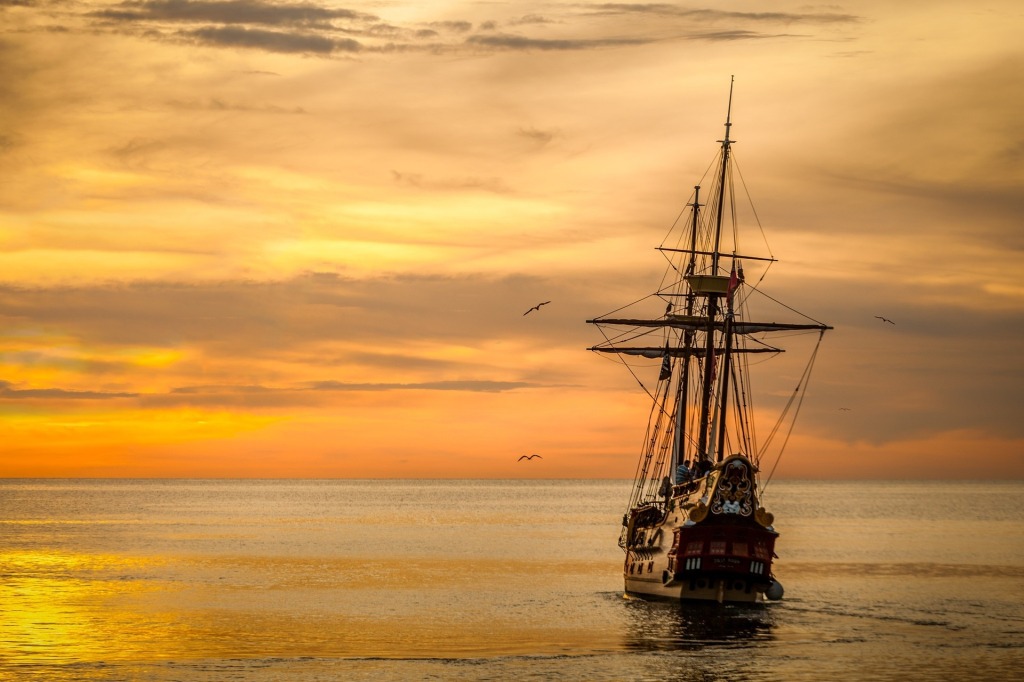 Ship sailing towards the horizon at sunset