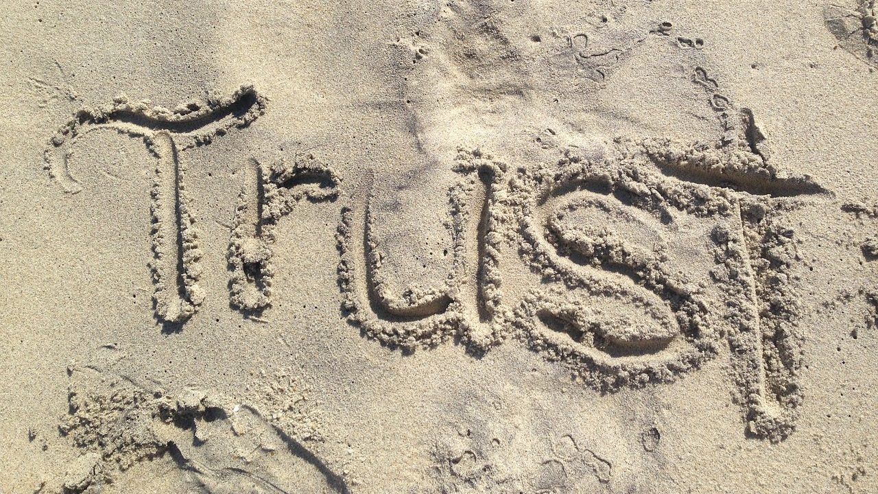 The word 'trust' written in sand